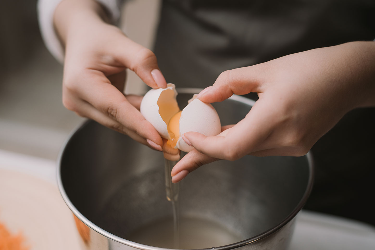female-cook-gray-apron-breaks-egg-metal-bowl-separate-protein-from-yolk